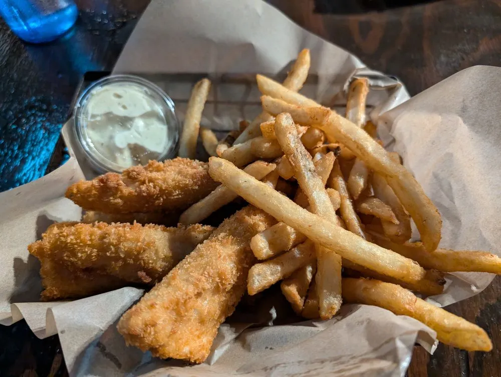 A basket of golden panko-crusted fish and chips with fries and house tartar.